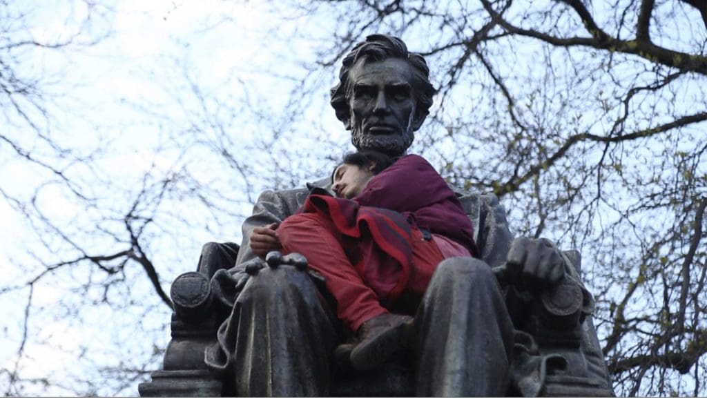 Photo of man sleeping on Abraham Lincoln statue.